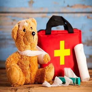 image of a teddy bear with a sling next to the first aid kit