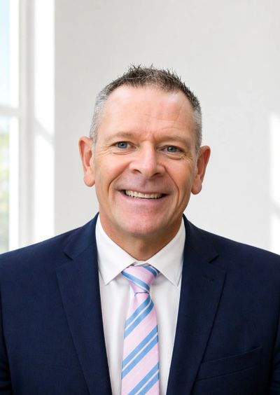 Smiling man in a suit with a striped tie.