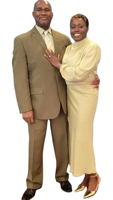 A well-dressed couple posing together, smiling warmly.