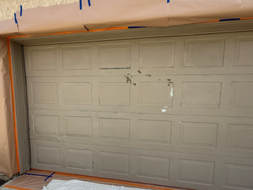 Garage door prepped for painting with protective paper and tape.