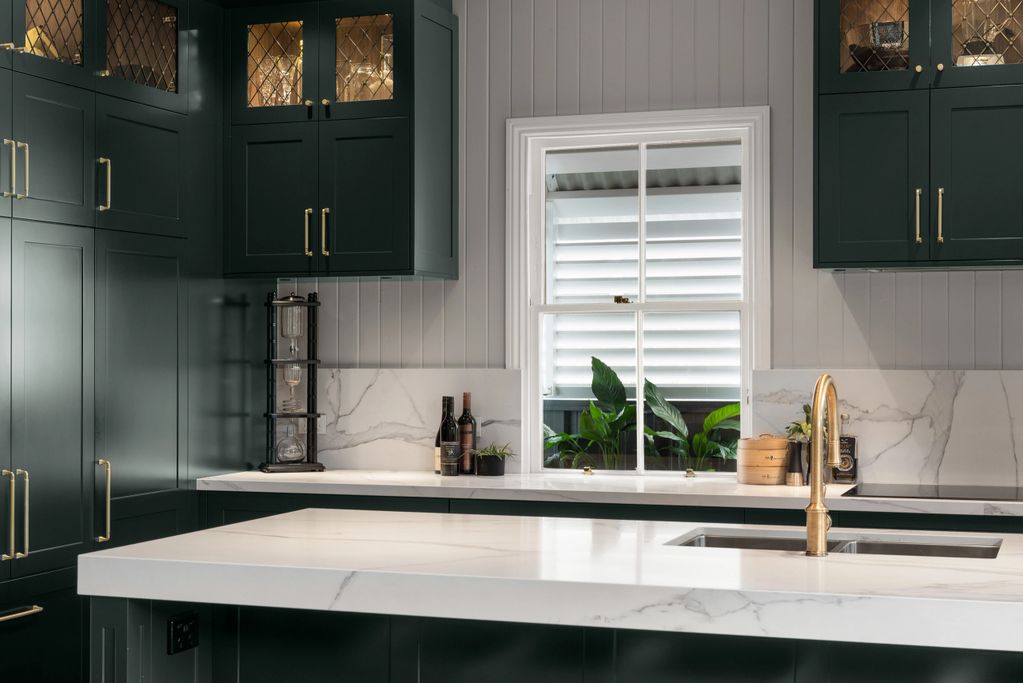 Queenslander kitchen with dark cabinets and light-veined stone benchtop