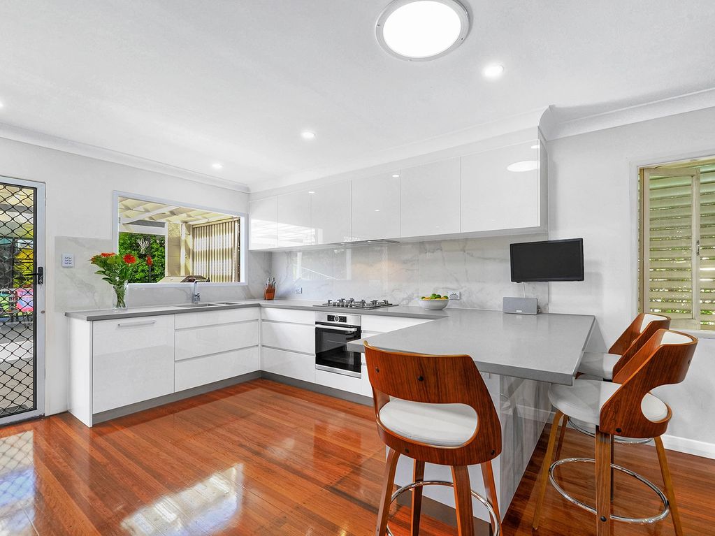 Modern white kitchen with handleless cabinets and timber floors