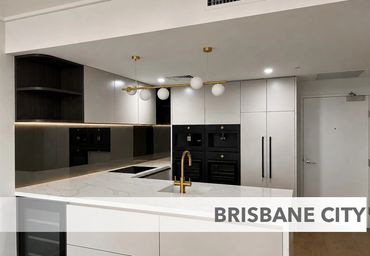 Modern white and black kitchen with gold fixtures and marble countertops.