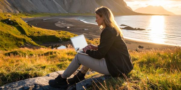 Woman working on laptop in a scenic outdoor setting.