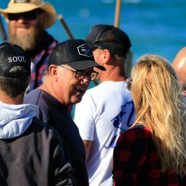 Group of people socializing outdoors near water on a sunny day.
