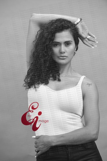 Black and white portrait of a confident woman with curly hair posing stylishly.