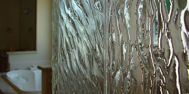 Close-up of custom made textured glass panel in a bathroom shower setting.