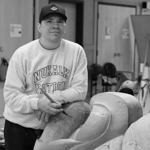 Man carving wood with brush in art studio.