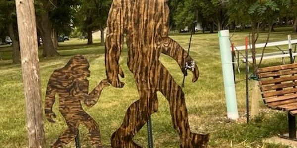 Wooden cutouts of Bigfoot figures in a park.