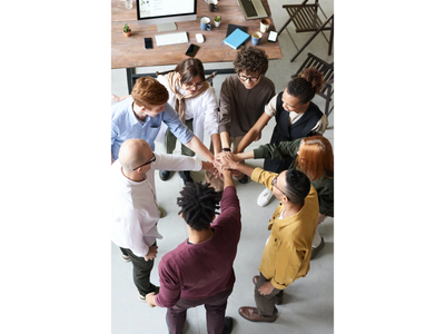 A picture of a group of people standing in a circle with their hands in the middle stacked up.