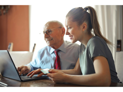 An older man and young woman sitting together looking at a computer.