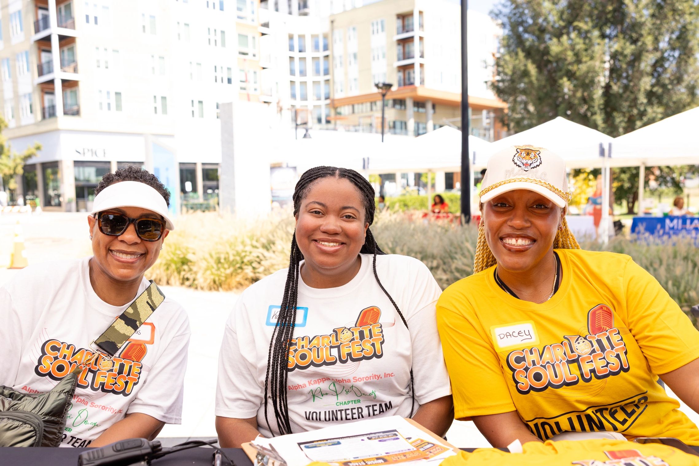 Three smiling women at Charlotte Soul Fest wearing volunteer shirts.