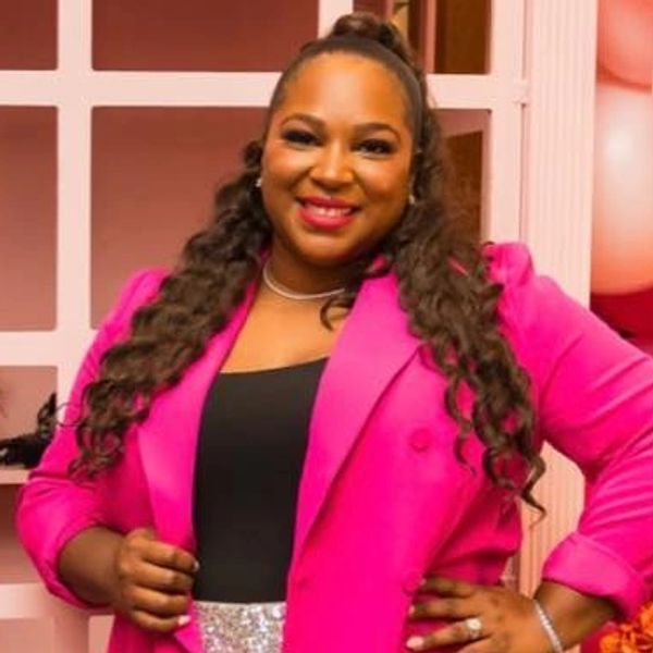 Woman smiling in a bright pink blazer.
