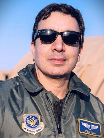 Man wearing sunglasses and a military jacket with patches.