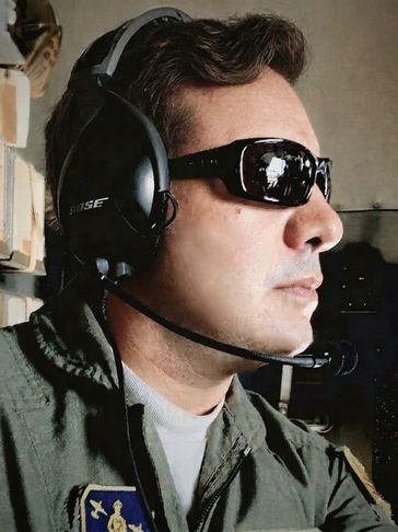 Man wearing pilot headset and sunglasses inside an aircraft.
