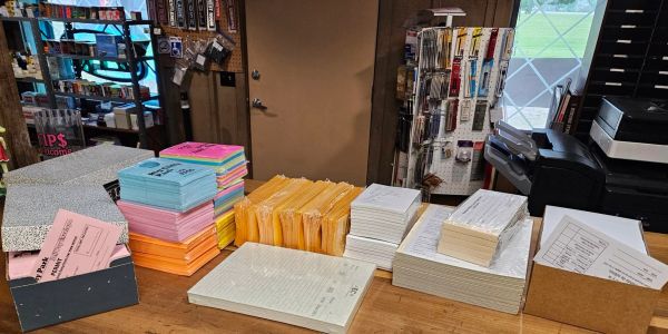 Stacks of colorful envelopes and paper on a wooden counter.