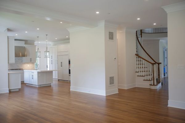 Spacious modern kitchen with white cabinetry and wooden floors.