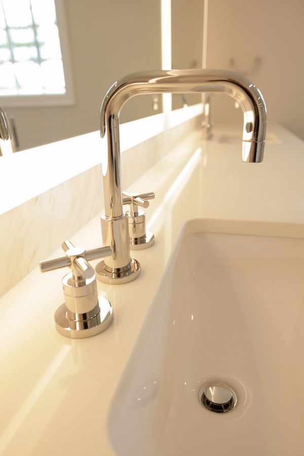 Close-up of a modern chrome bathroom faucet and handles on a white sink.