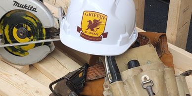 Construction tools and a hard hat with Griffin Academy logo on wooden planks.