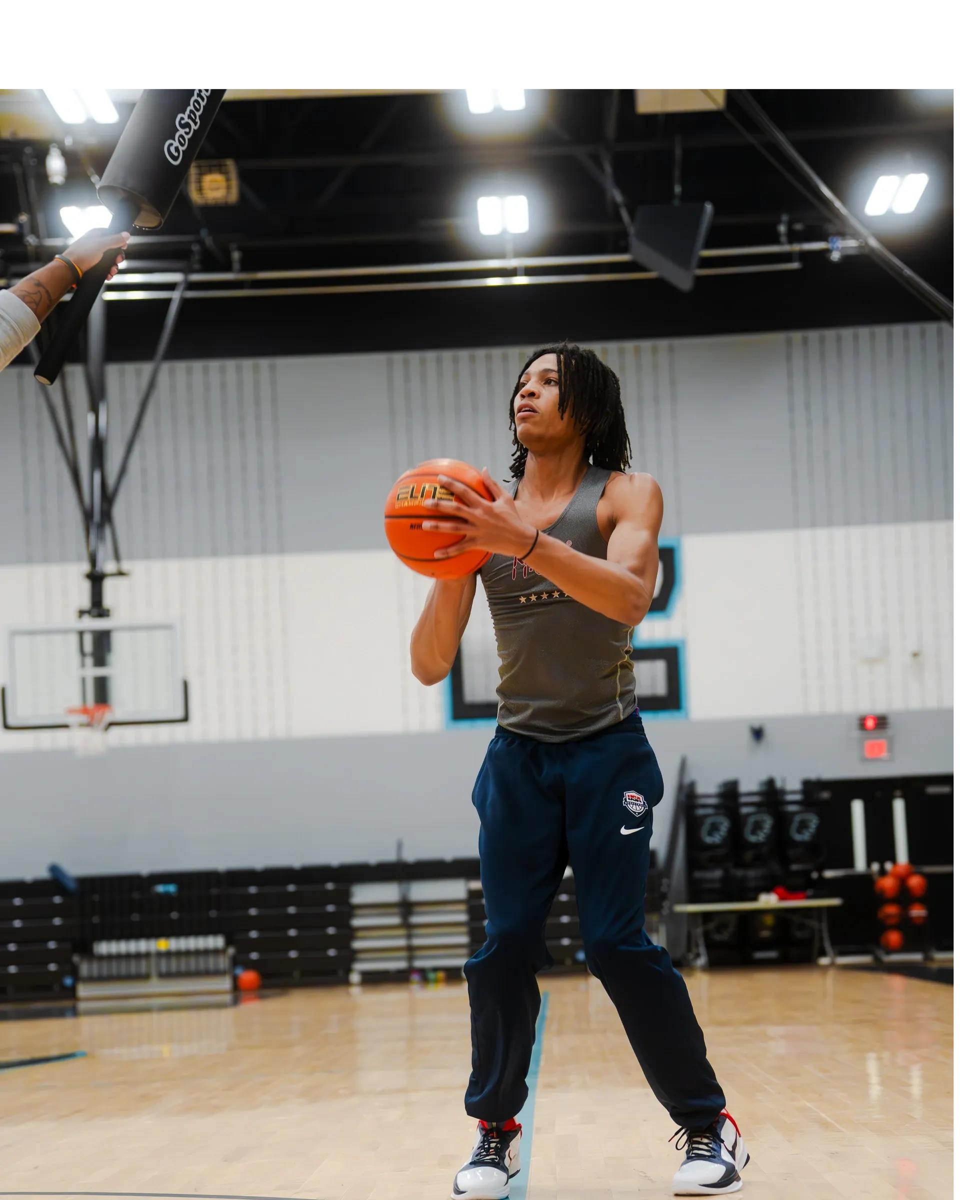 Young man preparing to shoot a basketball in an indoor gym.