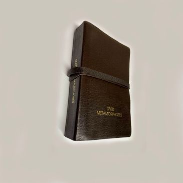 A black leather-bound book titled 'Ovid Metamorphoses' with a strap around it.