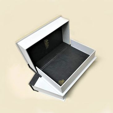 Elegant white and black gift boxes with gold accents, open to display their interiors.