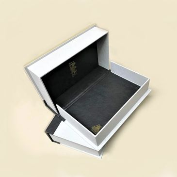 Elegant white and black gift boxes with gold accents, open to display their interiors.