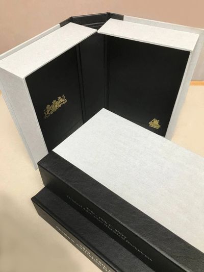 Elegant black and white luxury book boxes with gold embossed logos.