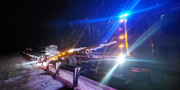 Flatbed rollback tow truck loading a disabled vehicle on the Kansas Turnpike