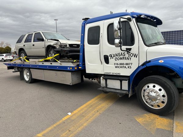 Towing service in Wichita Kansas with a flat bed rollback tow truck towing a wrecked car
