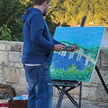 Man painting a landscape outdoors.