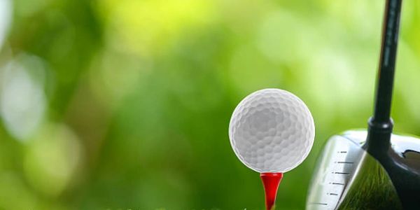 Golf ball on a red tee with a driver club ready to hit.