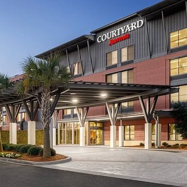 Courtyard Marriott hotel entrance with canopy and palm tree at dusk.