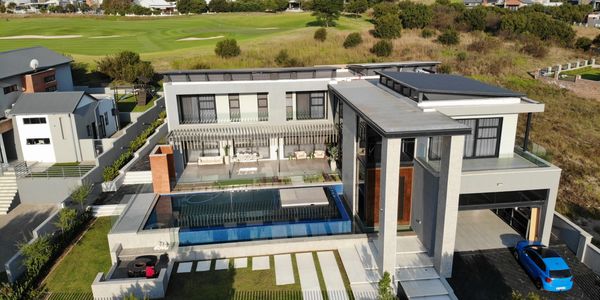 Modern luxury house with a pool and golf course view.
