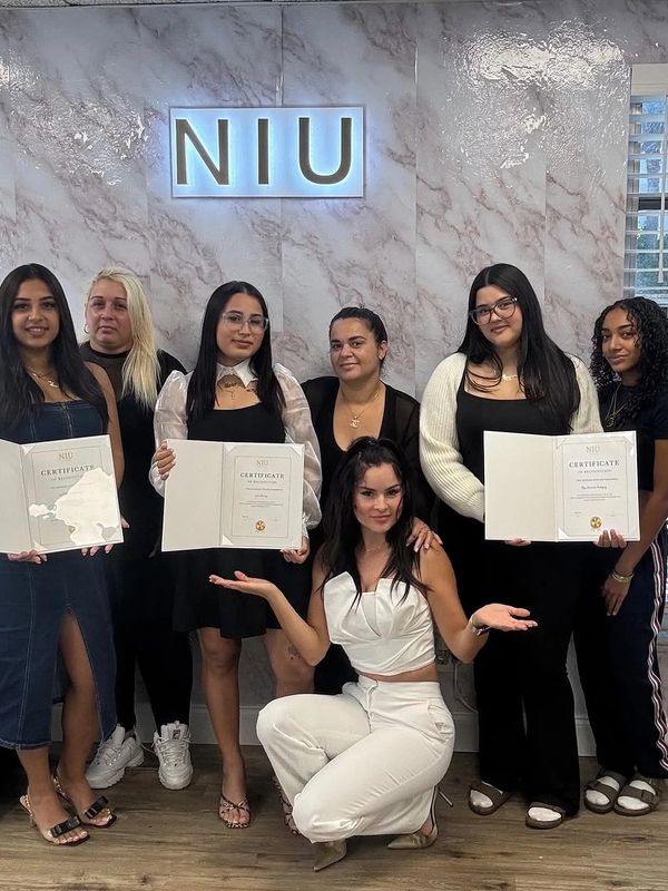 Group of women holding certificates in front of NIU sign.