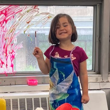Smiling girl painting on a window.