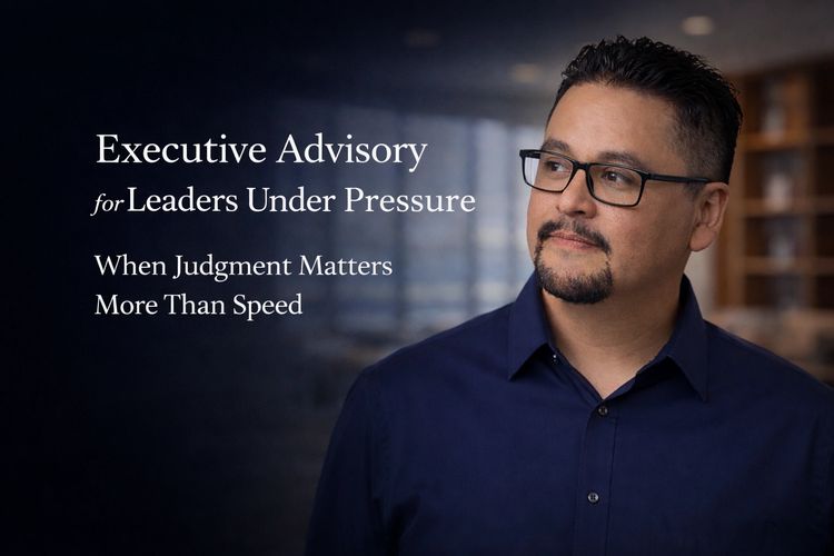 Portrait of Dr. Hugo Velazco, executive advisor in business psychology, standing in a modern professional environment, looking thoughtfully to the side, representing reflective decision-making under pressure.