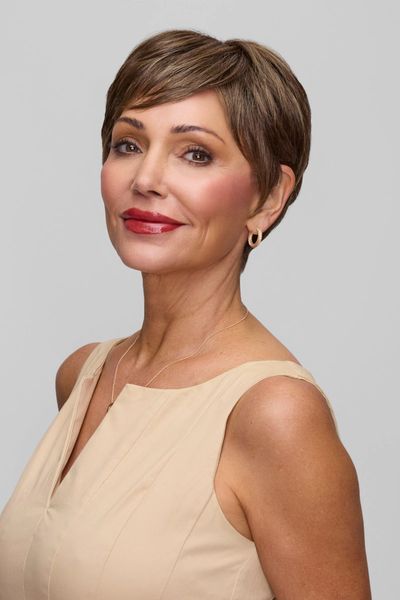 Confident woman with short hair in a beige sleeveless dress.