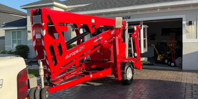 Red Europelift trailer lift parked in driveway in front of a garage.