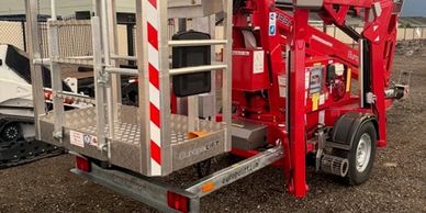 Red mobile hydraulic lift parked on a dirt surface.