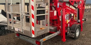 Red mobile hydraulic lift parked on a dirt surface.