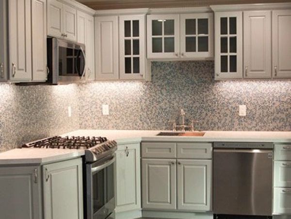 Modern kitchen with gray cabinets and stainless steel appliances.
