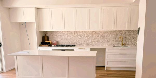Modern white kitchen with minimalist design and gold faucet.