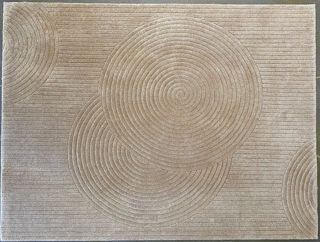 Beige rug with a spiral and linear pattern.