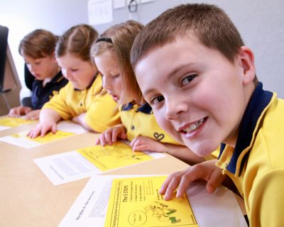 Young students in yellow school uniforms reading at a desk