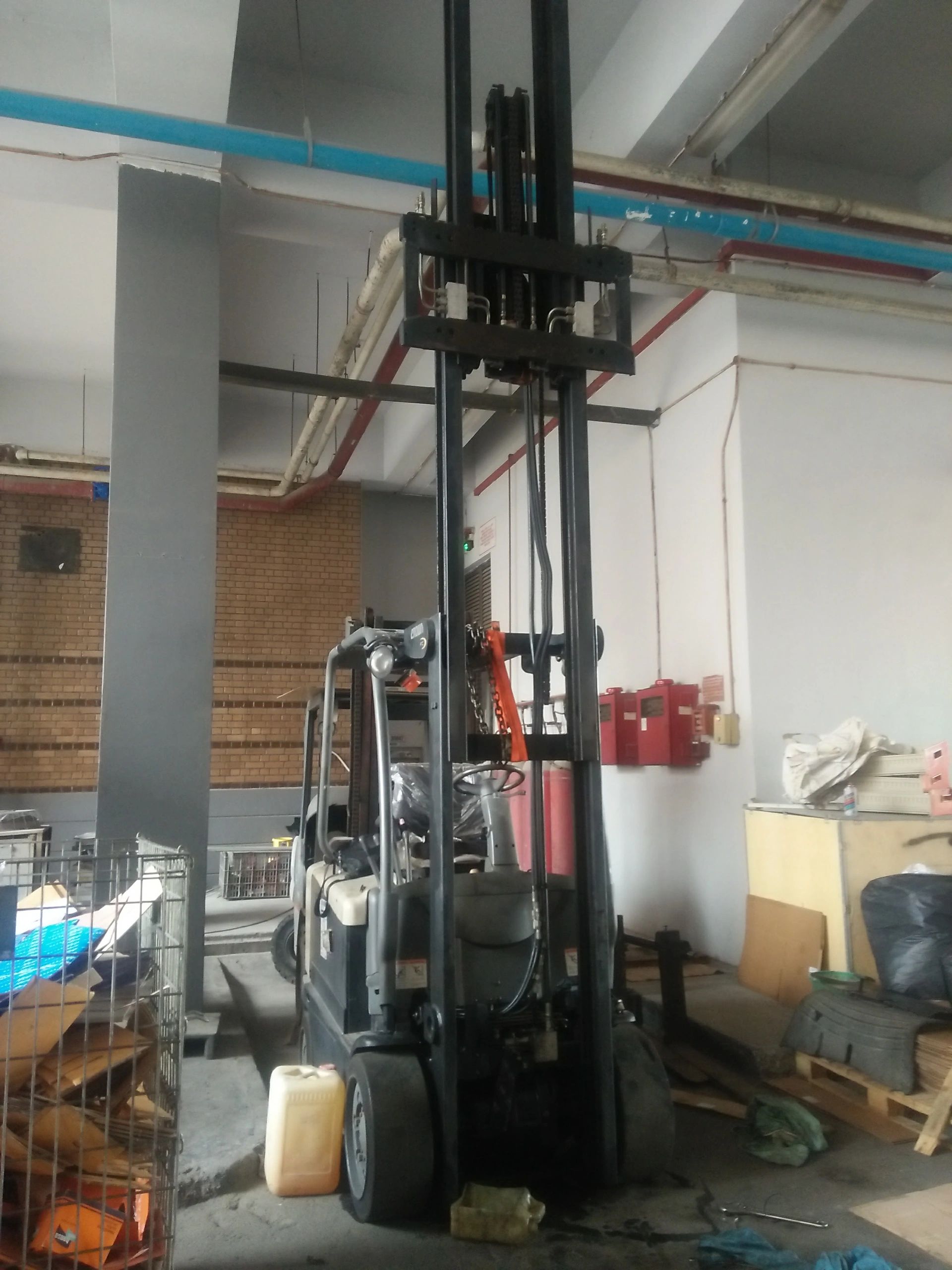 A forklift inside a warehouse with various stored items.