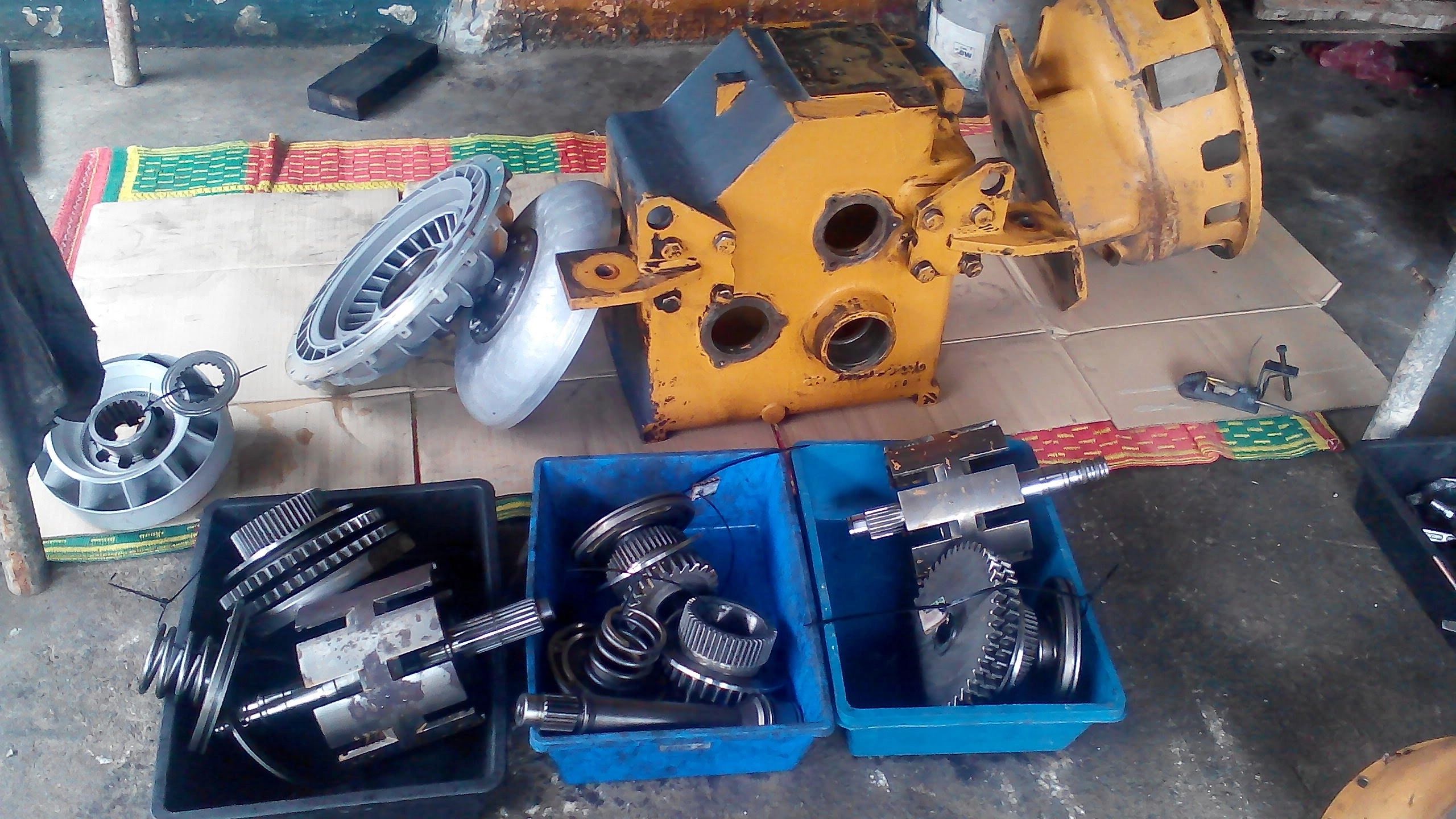 Disassembled mechanical parts and components in containers on the floor.
