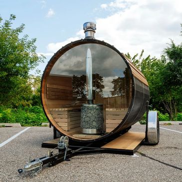 A mobile barrel sauna with a glass front, showing a heater inside.