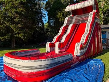 Inflatable red and white water slide on a blue tarp.