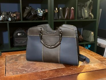 Stylish black leather handbag on a wooden table.